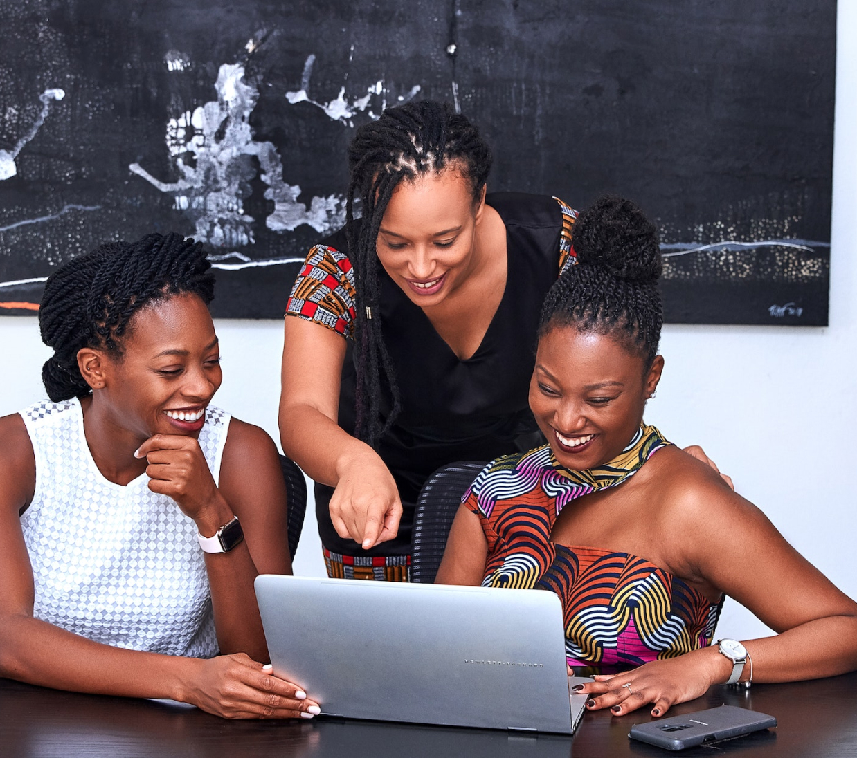 3 women looking at a laptop screen and smiling
